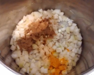 Photograph of a pan with a layer of diced onion and spices in the bottom