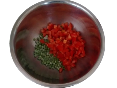 Photograph of a large mixing bowl with diced tomatoes and peas in